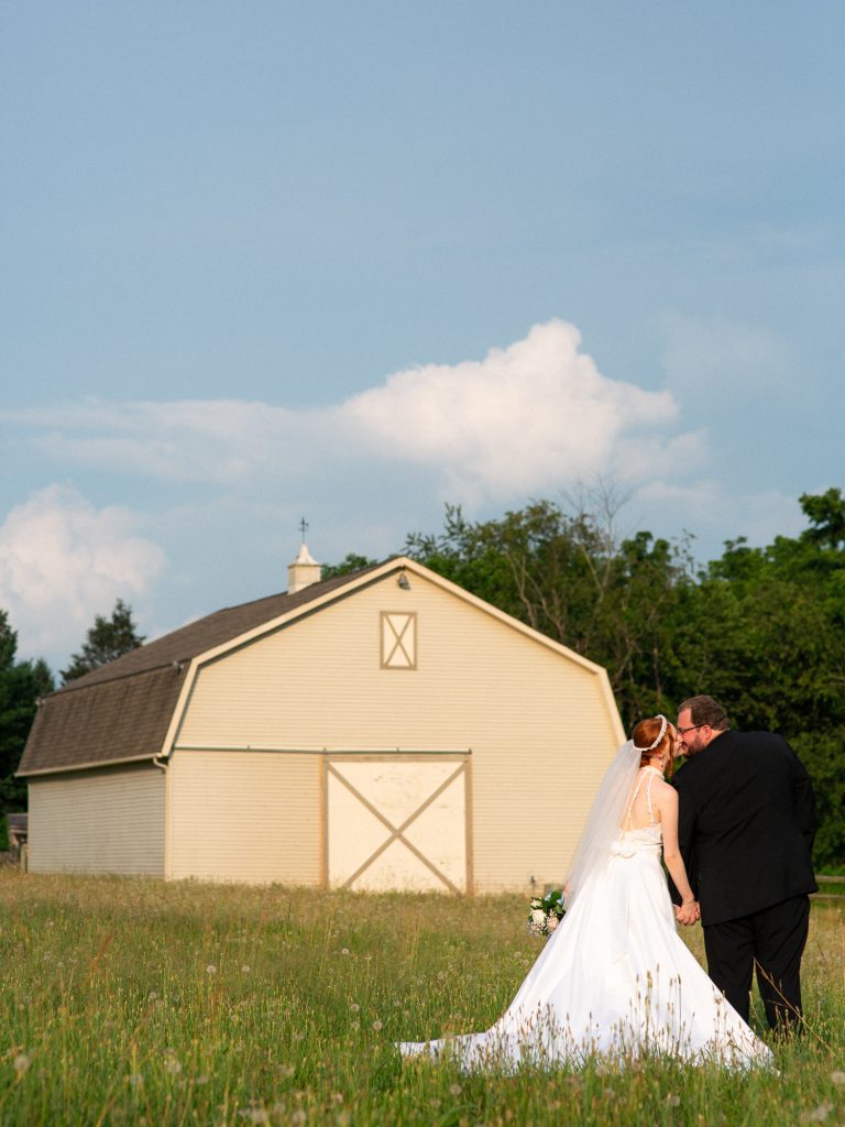 bride and groom kissing in front of a barn